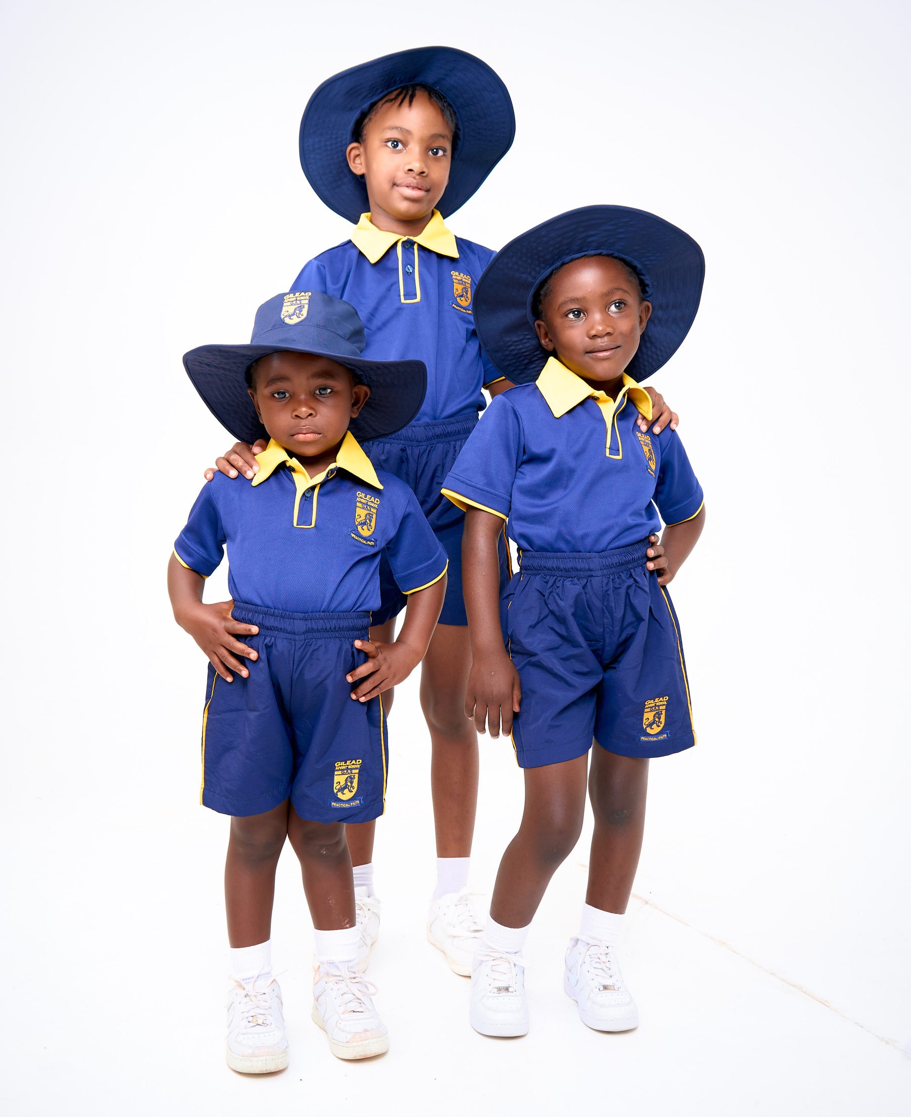 Children in Gilead Advent School navy and gold summer uniforms with wide-brim sun hats, manufactured by NECST